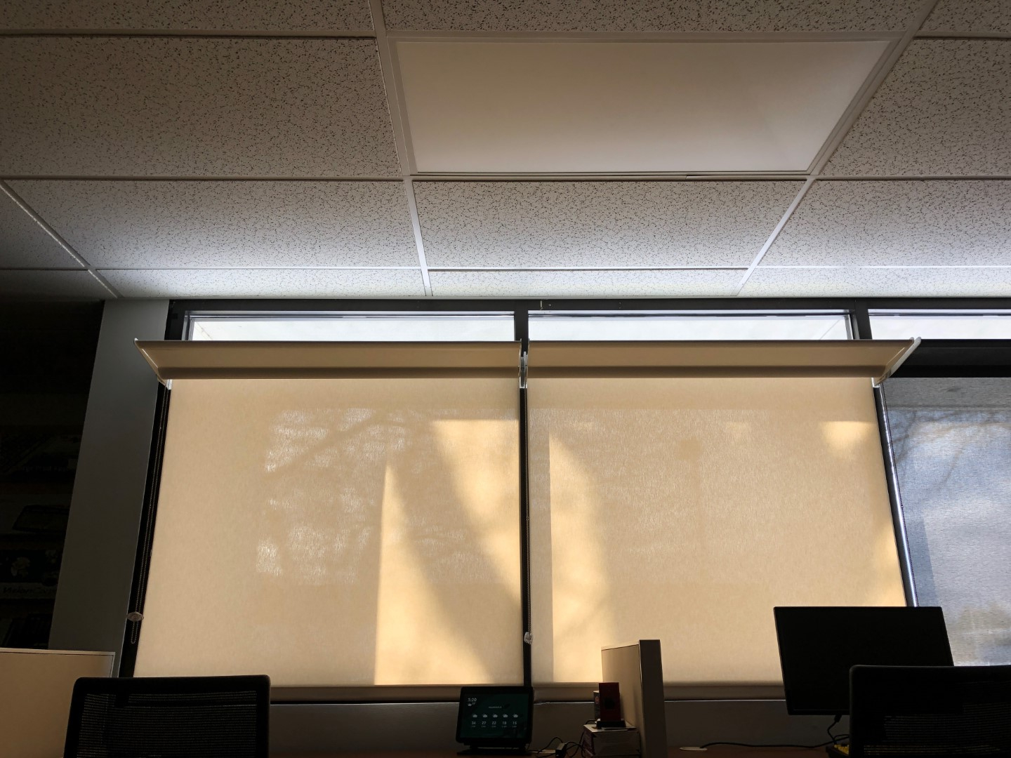 Office window  with shades drawn and lightshelf open. Daylight spreads across the ceiling.